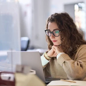 Professional woman researching commercial roofing services in Minnesota b2b market on laptop